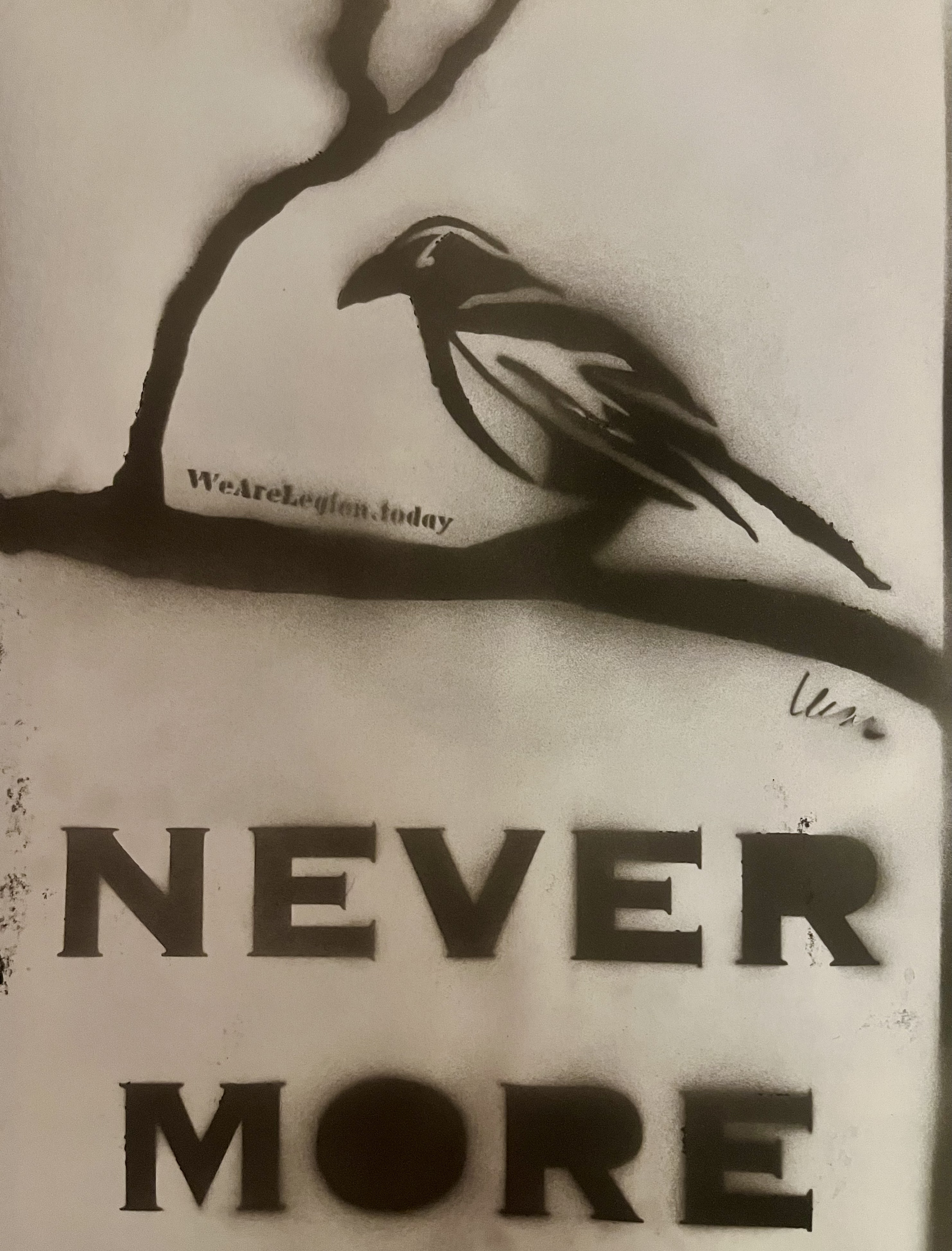 an image of a black spray painted stencil of a raven on a tree branch above the word NEVERMORE in bold type